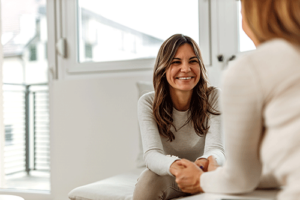 Woman smiles while talking to therapist in aftercare treatment program